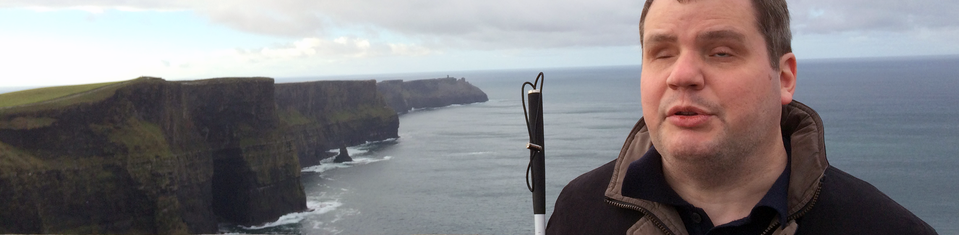 A blind mom smiles with her child in a carrier.